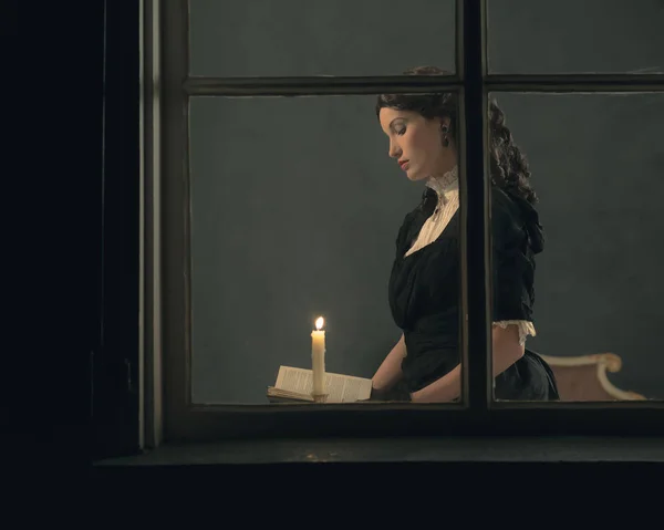 Mulher lendo livro à luz de velas — Fotografia de Stock