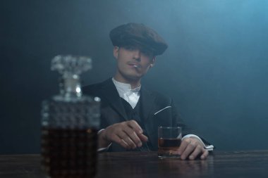 Viski ile masada oturan gangster.   