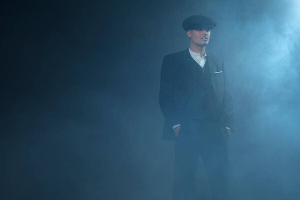 Гангстер в плоской кепке в дымовой комнате
. 