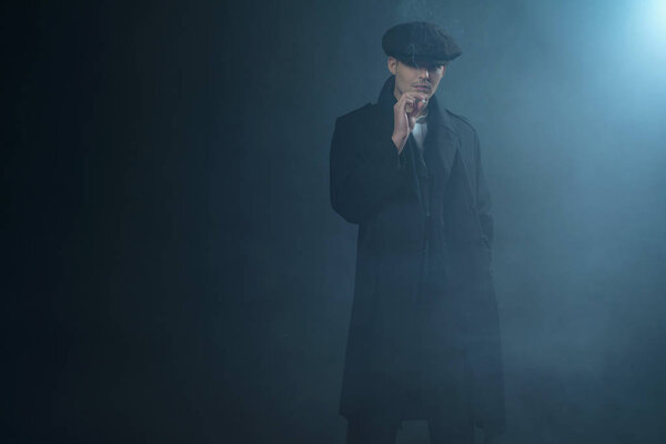 Гангстер в плоской кепке в дымовой комнате
. 