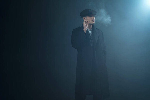 Гангстер в плоской кепке в дымовой комнате
. 