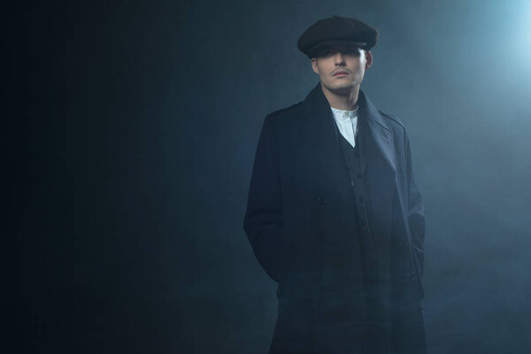 Гангстер в плоской кепке в дымовой комнате
. 