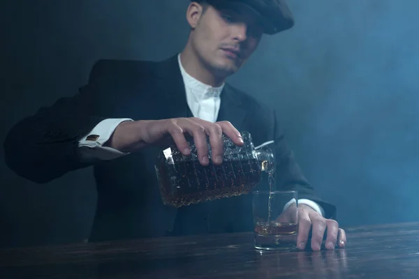 Gangster s ploché víčko nalévání whisky. — Stock fotografie