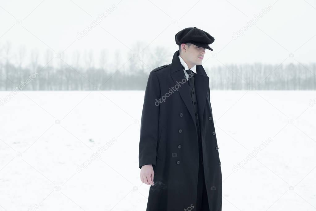 Gangster with cigarette in winter snow landscape.  