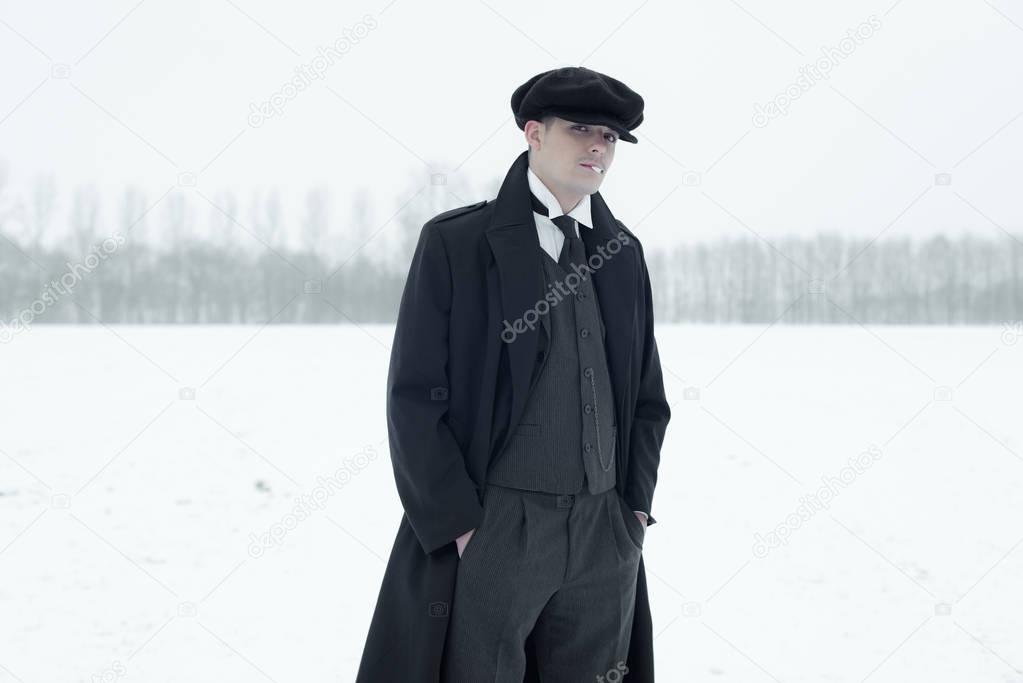 Gangster with cigarette in winter snow landscape.   