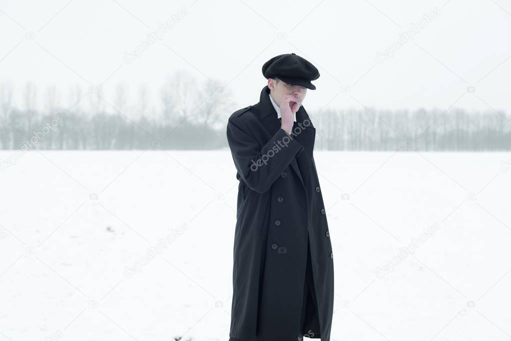 Gangster with cigarette in winter snow landscape.    