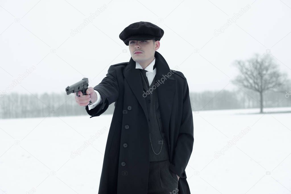 Gangster shooting with gun in winter. 