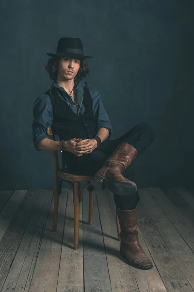 Man wearing hat sitting on chair — Stock Photo, Image