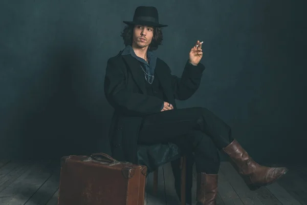 Muž na sobě klobouk a kabát kouření — Stock fotografie