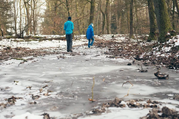 Man and woman standing on frozen puddles — Stock Photo, Image