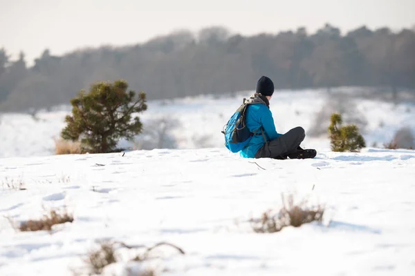 Чоловік з рюкзаком сидить у снігу — стокове фото