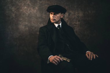 Sandalyede oturan silahlı gangster