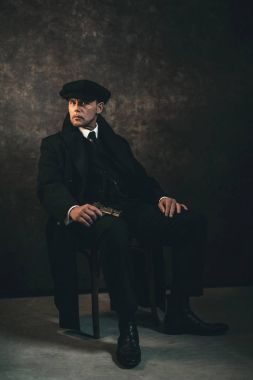 Sandalyede oturan silahlı gangster