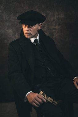 Sandalyede oturan silahlı gangster