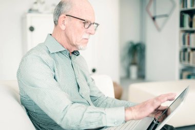 Dizüstü bilgisayarla çalışan kıdemli adam. 