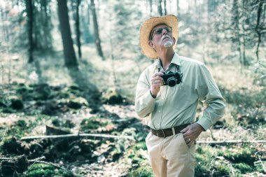 Adam ağaçlara bakarken kamera ile 