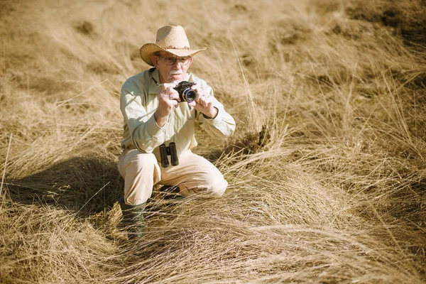 Starší muž s fotoaparátem v gras — Stock fotografie