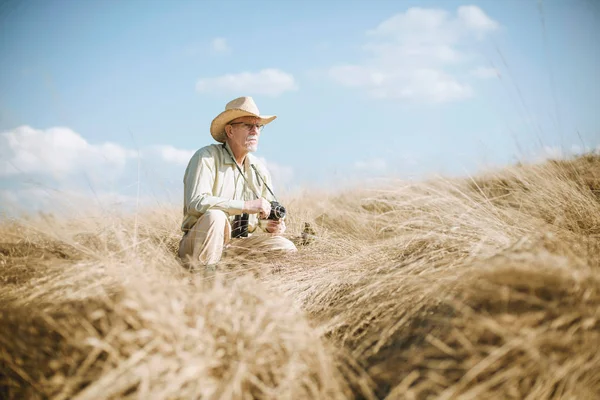 Senior man met camera in gras — Stockfoto