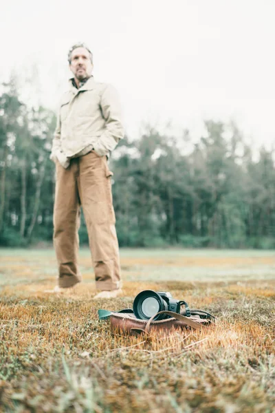 Uomo in piedi dietro la borsa in pelle con fotocamera — Foto Stock