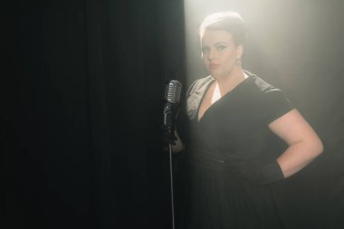 kadın dumanlı sahnede mikrofon ile