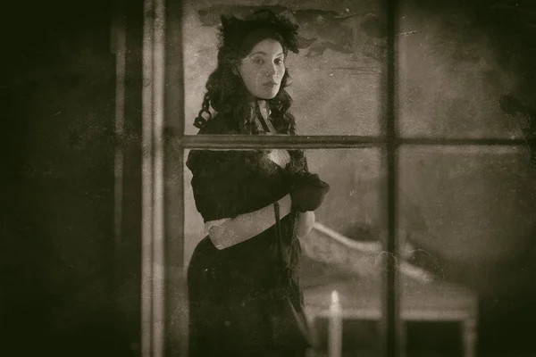 Mulher de vestido preto atrás da janela — Fotografia de Stock