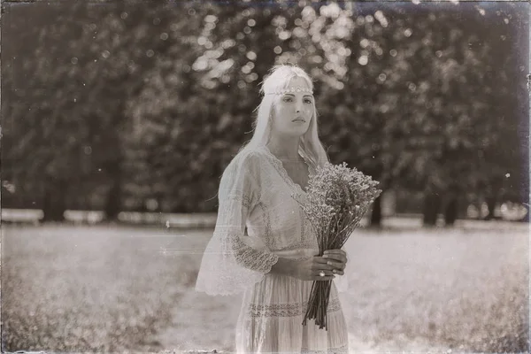 Blonde bride with bouquet in park — Stock Photo, Image