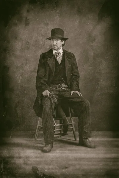 mature man with revolver sitting on stool