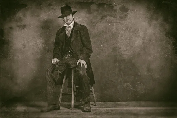 Taburede oturan tabanca ile olgun adam