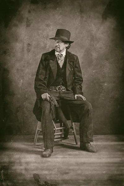 Taburede oturan tabanca ile olgun adam