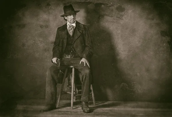 Zralý muž s revolverem sedí na stoličce — Stock fotografie