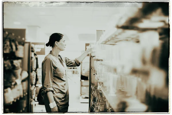 Женщина в магазине смотрит на посуду — стоковое фото