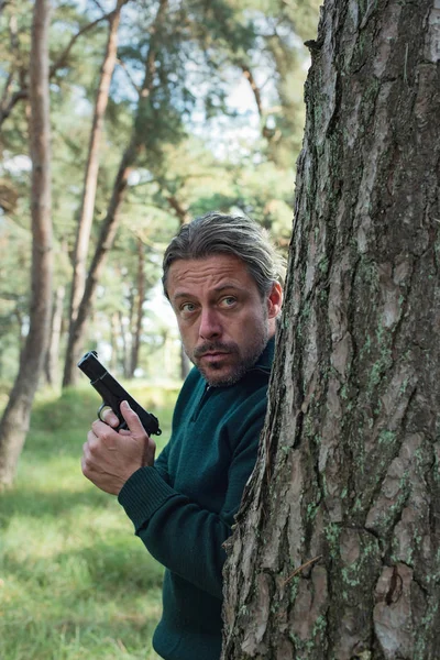 Man with pistol in forest