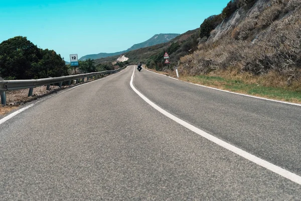 คนขี่มอเตอร์ไซค์ขับรถบนถนนภูเขา — ภาพถ่ายสต็อก