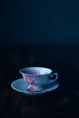 kirli kanlı beyaz çay bardağı ve tabağı koyu ahşap masa üzerinde 
