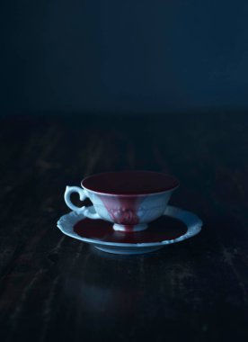 koyu ahşap masa üzerinde kan olan beyaz çay bardağı dolu 