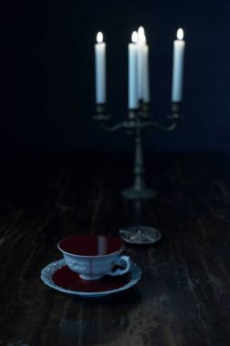 kan muska ve koyu ahşap masa üstünde şamdan mumlar yanan ile beyaz çay bardağı dolu 