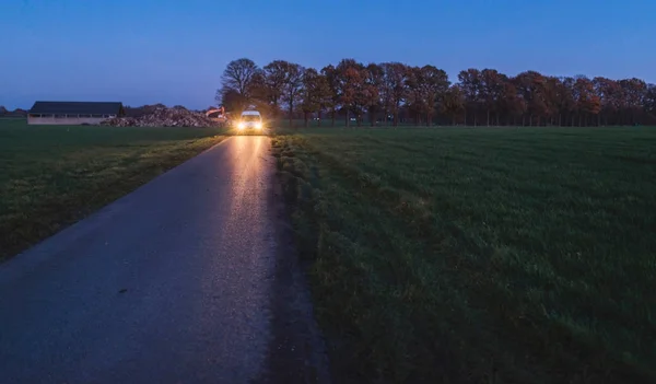 Vehicle with headlights on country road — Stock Photo, Image