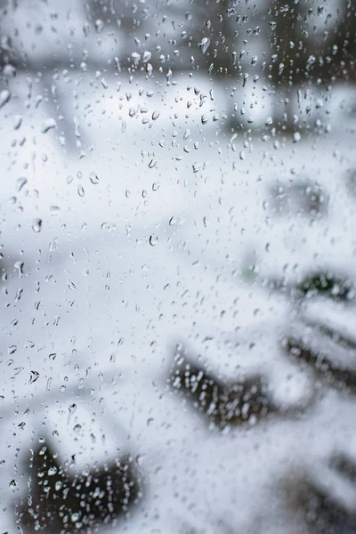 Raindrops on window with snowy garden — Stock Photo, Image