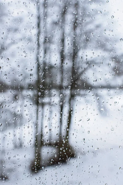 Raindrops on window with snowy garden