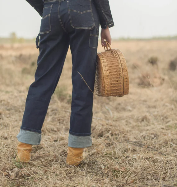 Жінка в джинсах тримає плетену сумку — стокове фото