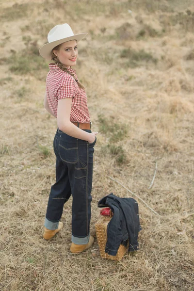 Smiling retro cowgirl with wicker basket — Stock Photo, Image