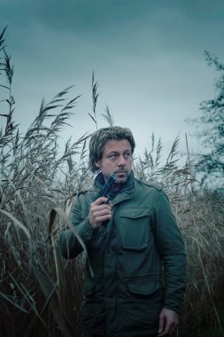 Sazlığın arasında silahlı bir adam..