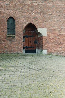 Penceresi ve ahşap kapısı olan bir kilise duvarı..