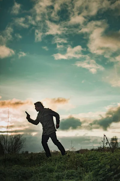 Man met pistool op het platteland bij zonsondergang. — Stockfoto