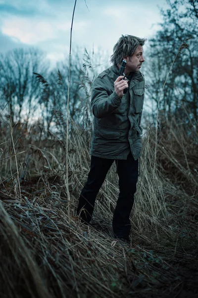 Man met pistool tussen riet op bewolkte dag. — Stockfoto