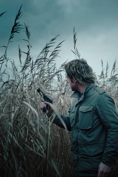 Man with pistol between reed. — Stockfoto