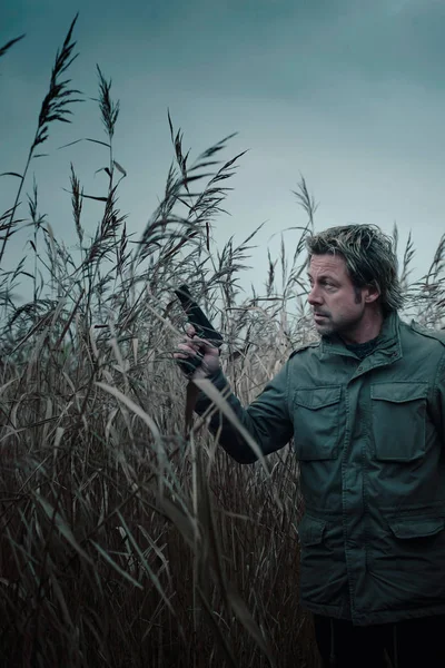 Hombre con pistola entre juncos . —  Fotos de Stock