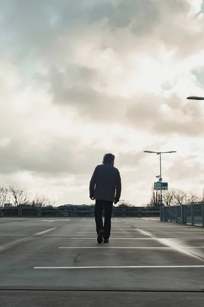 Homme sur le parking avec ciel nuageux. Vue arrière . — Photo