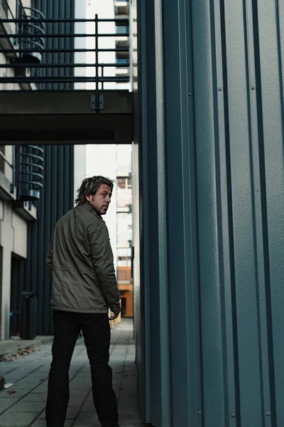 Man in green jacket standing in industrial area. — Stock Photo, Image