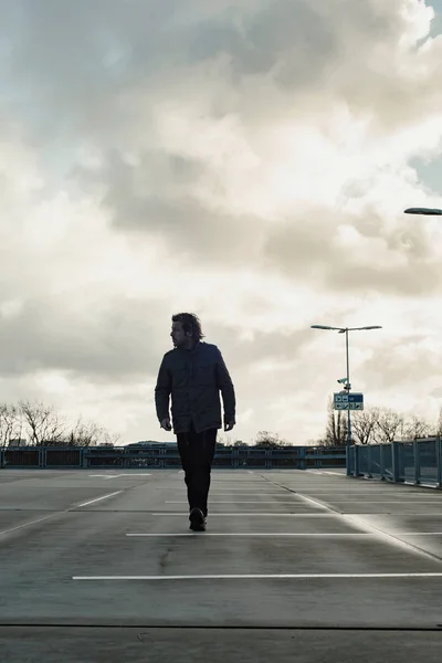 Man inspecting parking lot with cloudy sky. — Stock Photo, Image